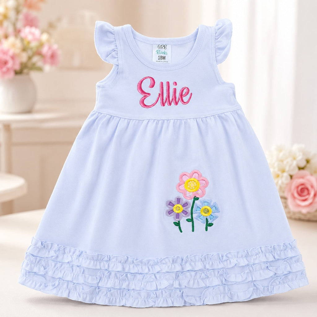 Light blue dress with embroidered flowers and name 'Ellie' on a neutral background