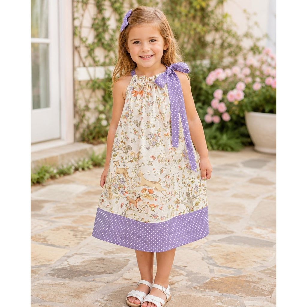 Young girl wearing a floral dress with purple accents outdoors.