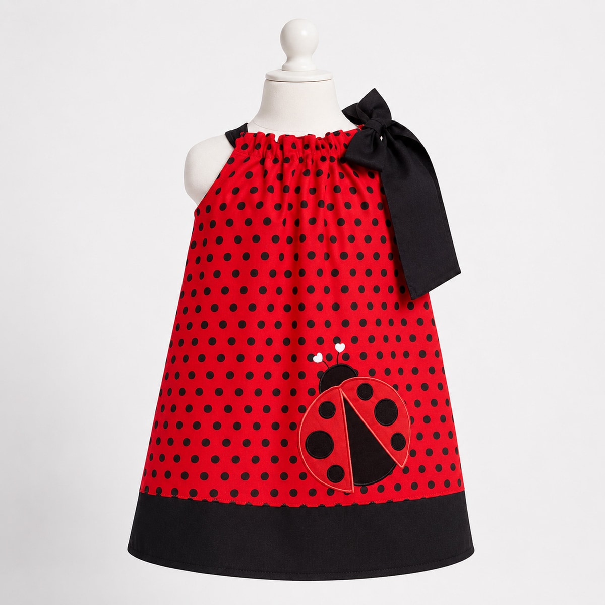 Red polka dot dress with a ladybug design on a mannequin against a white background