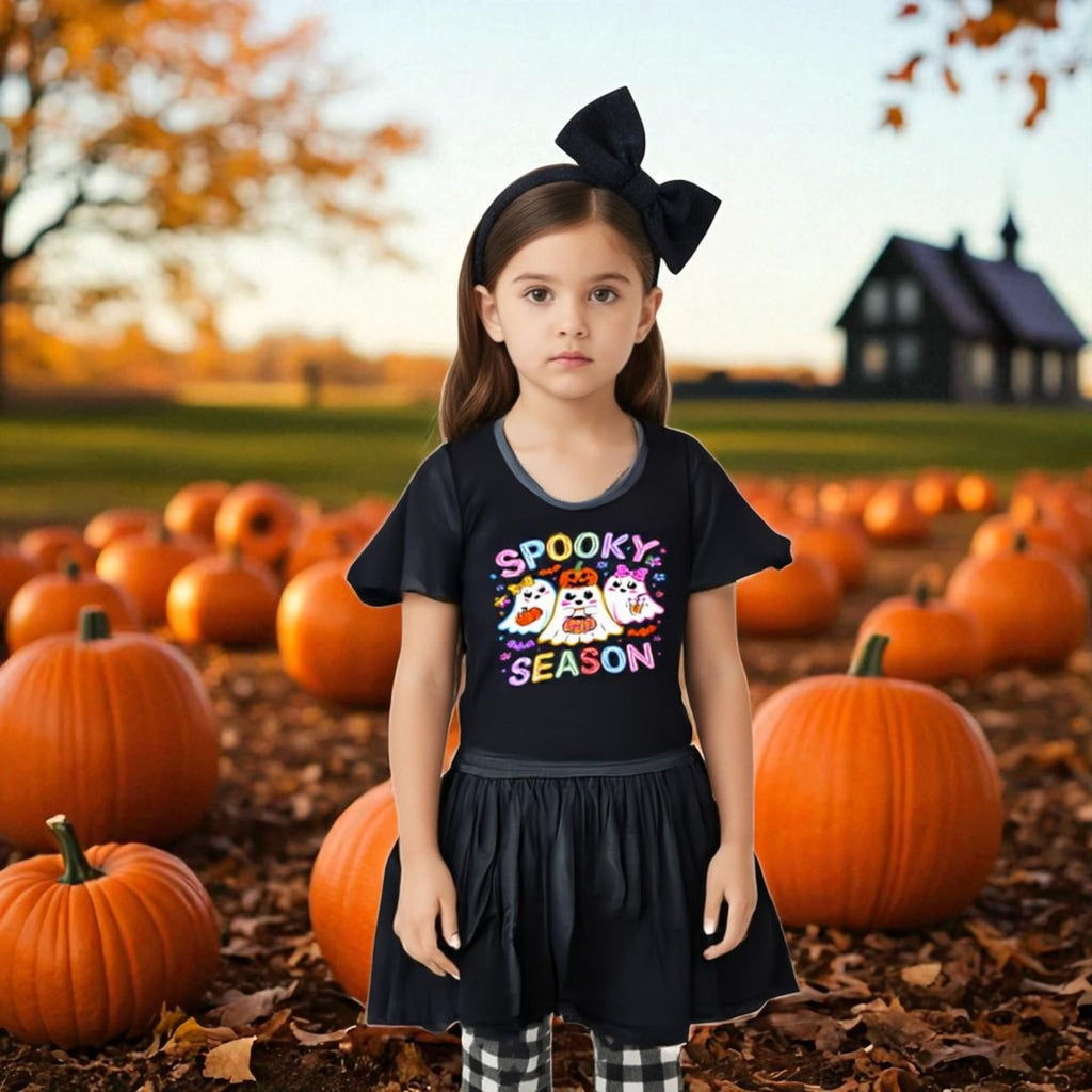 Young girl in a pumpkin patch wearing a 'Spooky Season' shirt.
