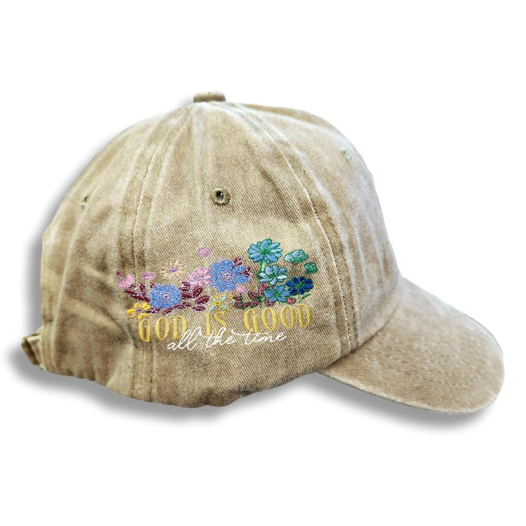 Beige cap with floral design and 'God is good all the time' text on a white background